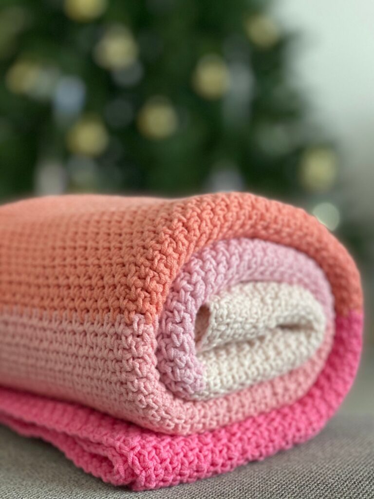Gerollte gehäkelte Decke in Rosa- und Orangetönen